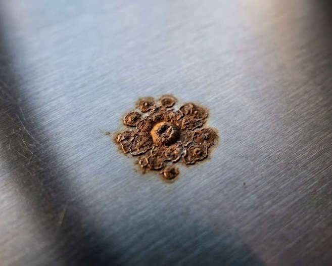 Macchia di ruggine su acciaio inox che simboleggia il fascismo come malattia latente