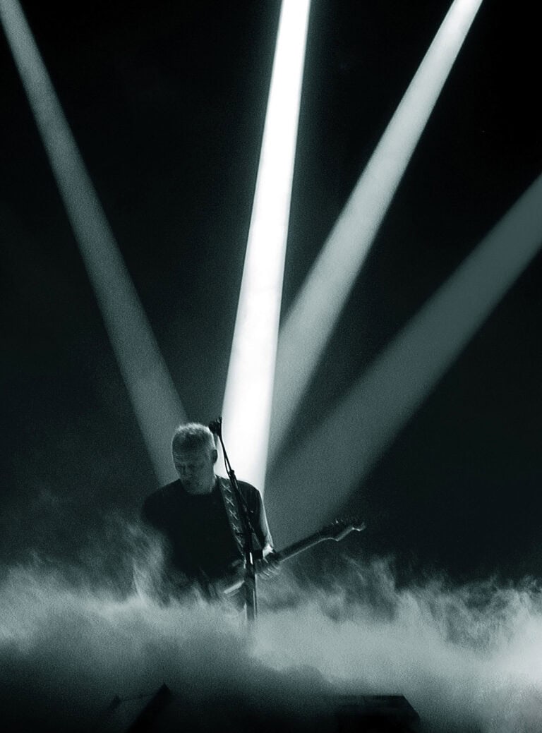 David Gilmour plays guitar in Munich July 2006 surrounded by lights in a dark background.