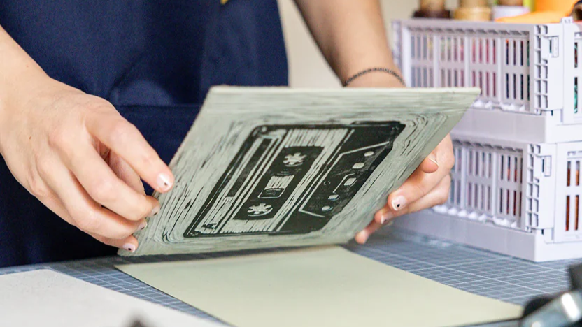 Laura Alfonsi mostra la matrice di linoleum incisa a mano con il disegno dell'audiocassetta, nel laboratorio Saimai di legatoria artigianale