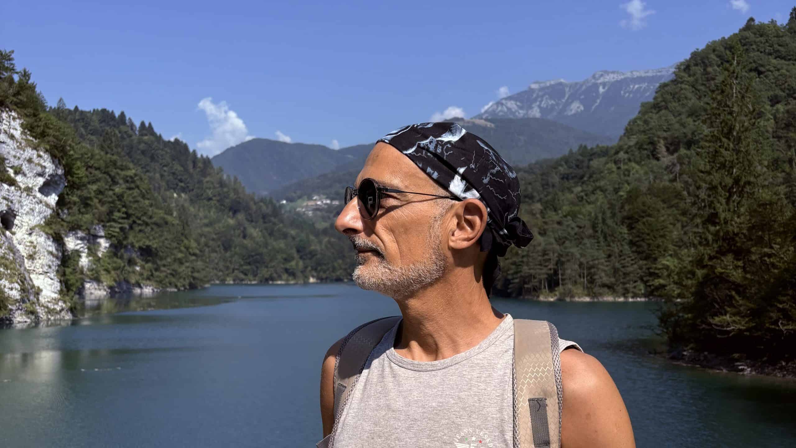 Persona in primo piano davanti a un lago alpino e alle montagne: ricordati che devi morire che tenere vicini i pensieri positivi